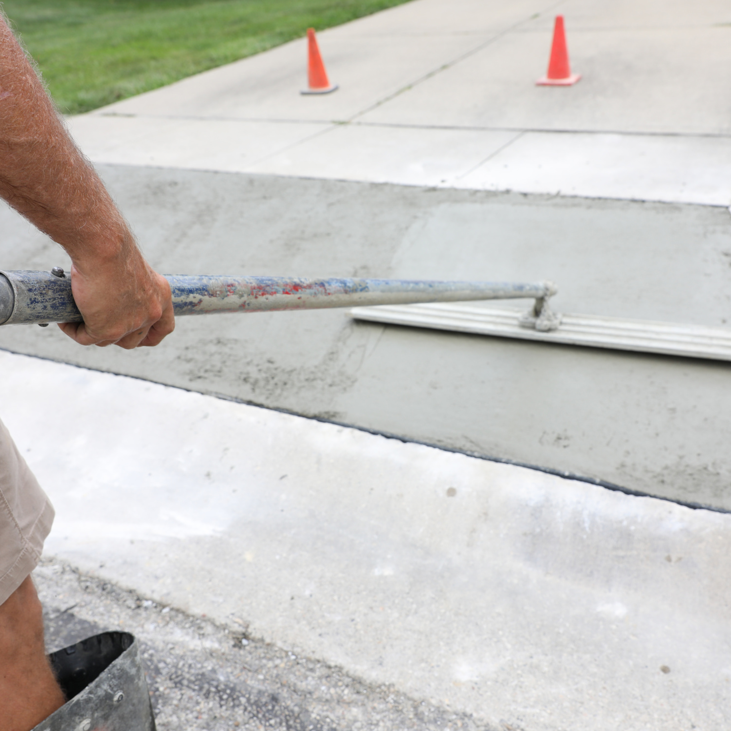 Fresh concrete being floated in a replaced section between older driveway slabs